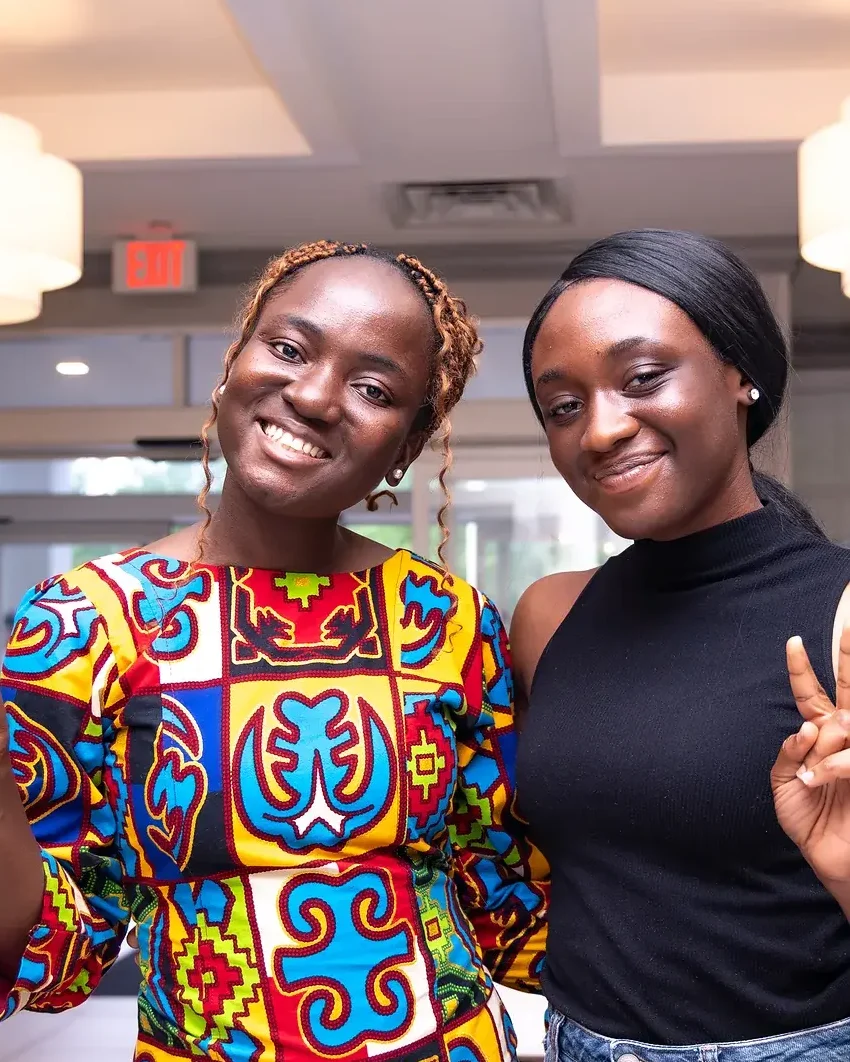 Two Cohort 1 students smiling and making peace signs at HerWebCraft Academy