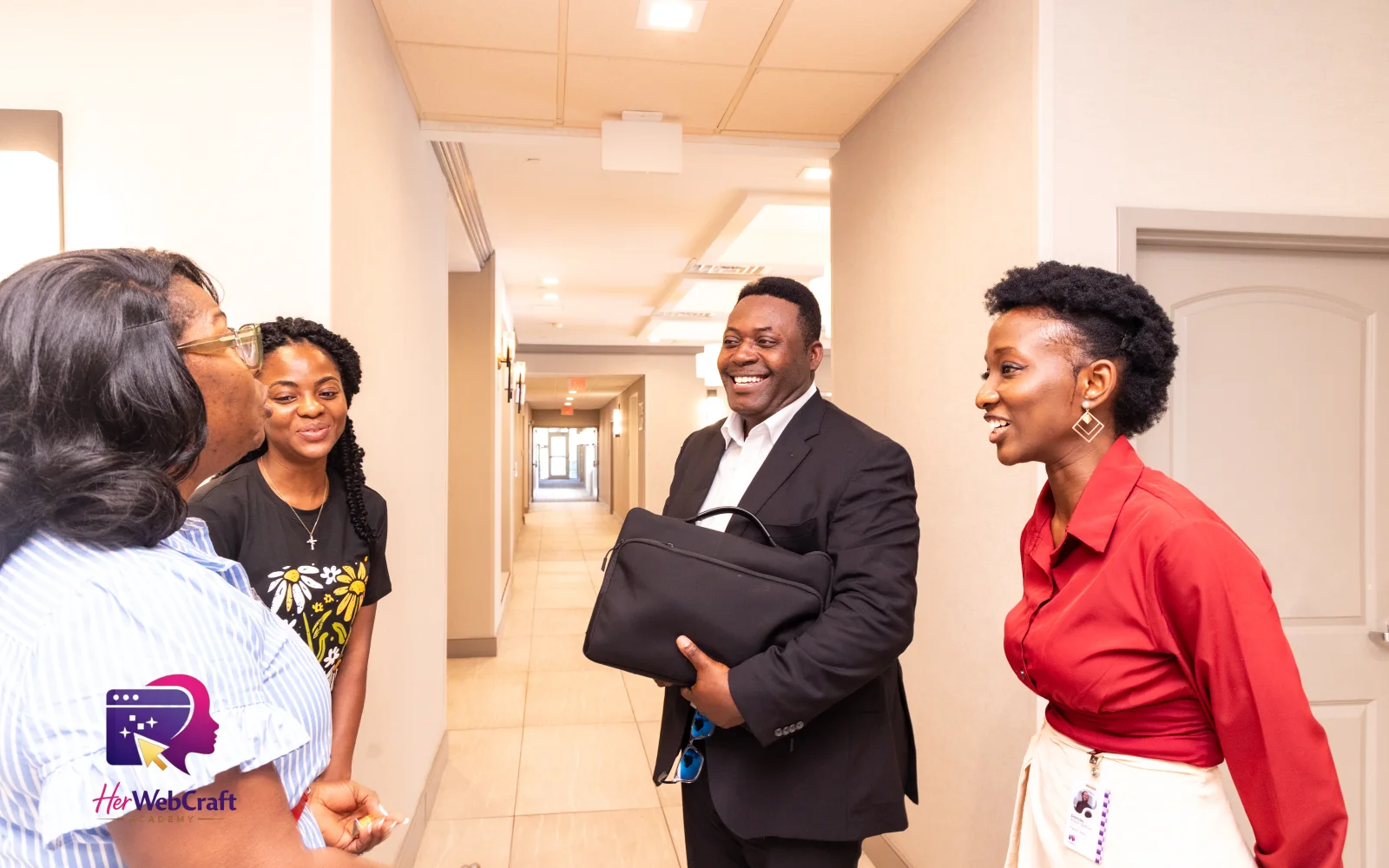 HerWebCraft Academy team members and a student greeting a guest in the hallway during Cohort 1